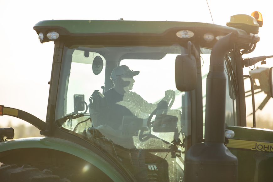 Grower driving tractor in field during spring