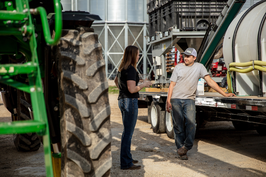 Farmer and retailer talking by tractor. 