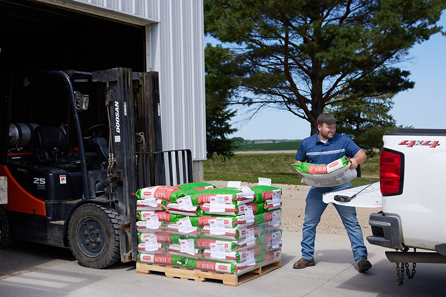 Retailer loading CROPLAN alfalfa seed into a pickup truck.